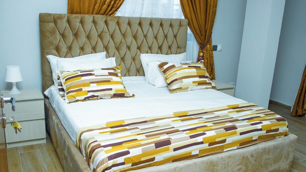 A bed with a tufted headboard, white bedding, and striped pillows.