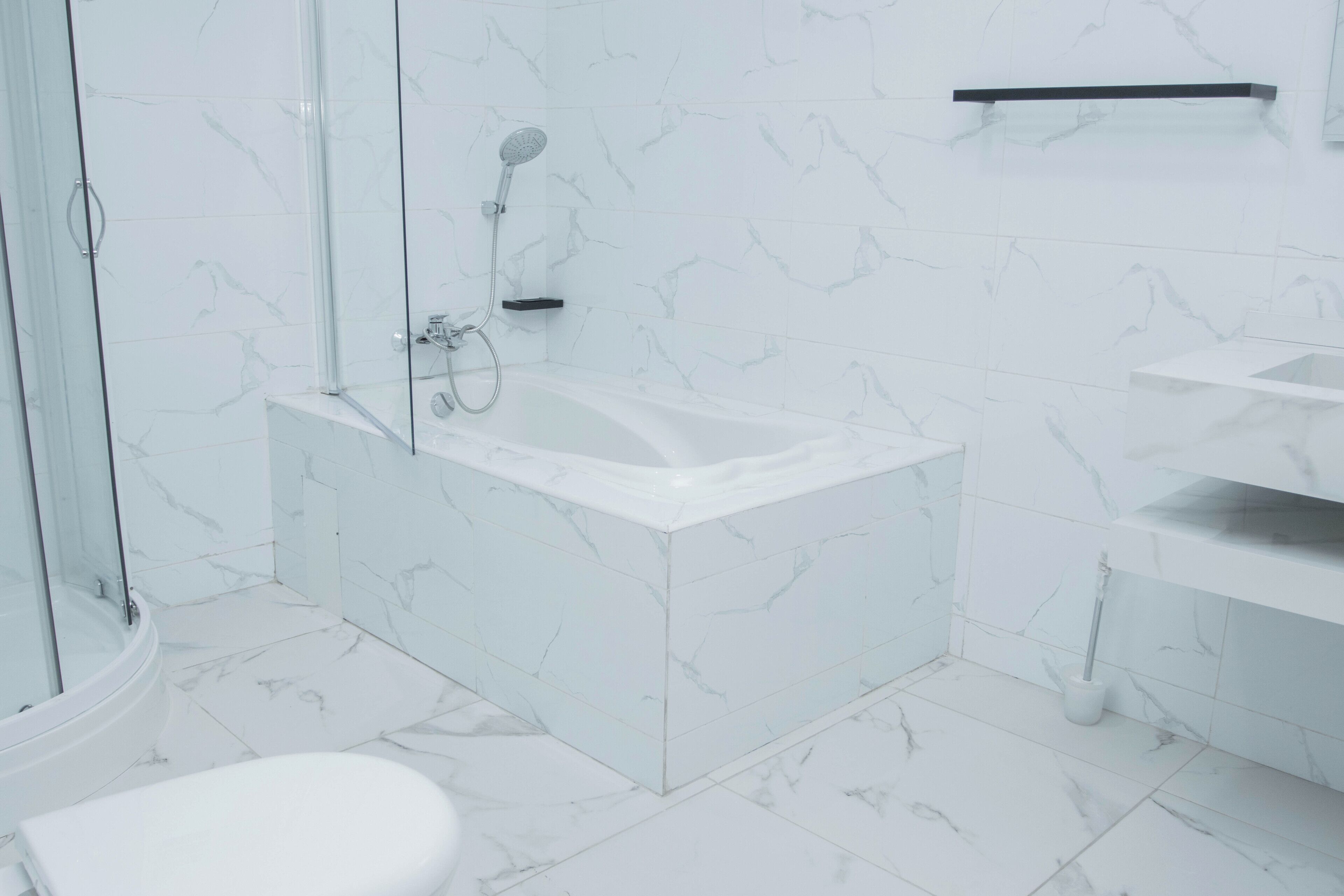 Un bagno moderno con cabina doccia in vetro, una vasca da bagno bianca e un water.