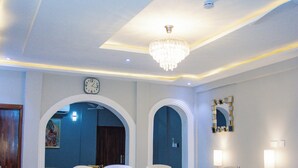 A modern dining area with a chandelier, a clock, and a dining table with chairs.