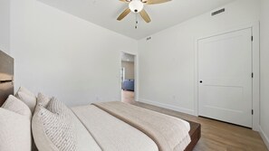 A bedroom with a bed, a ceiling fan, a door, and a hallway leading to another room. - Two Bottles Inn - Palisade Wine Country Retreat Signature Suite Balcony 10 (Palisade)