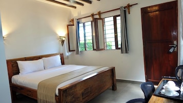Un dormitorio con cama de madera, mesita de noche, ventana con cortinas y una puerta.