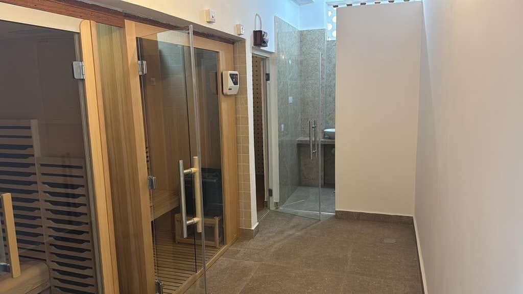 A bathroom with a glass shower enclosure, a toilet, and a sink.