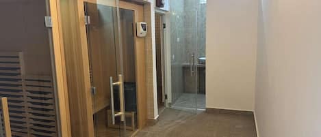 A bathroom with a glass shower enclosure, a toilet, and a sink.