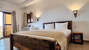 A bedroom with a wooden bed, a ceiling fan, and two wall-mounted lights.
