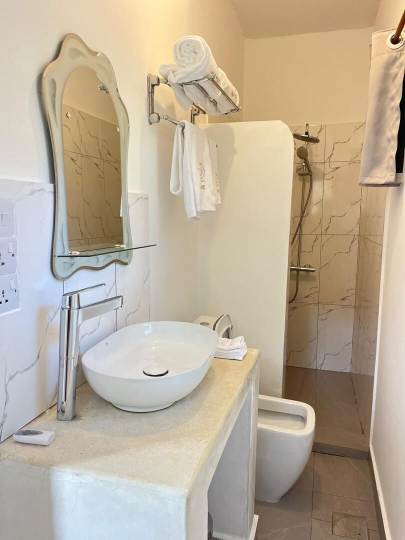 A bathroom with a white sink, a mirror, a towel rack, and a shower area.