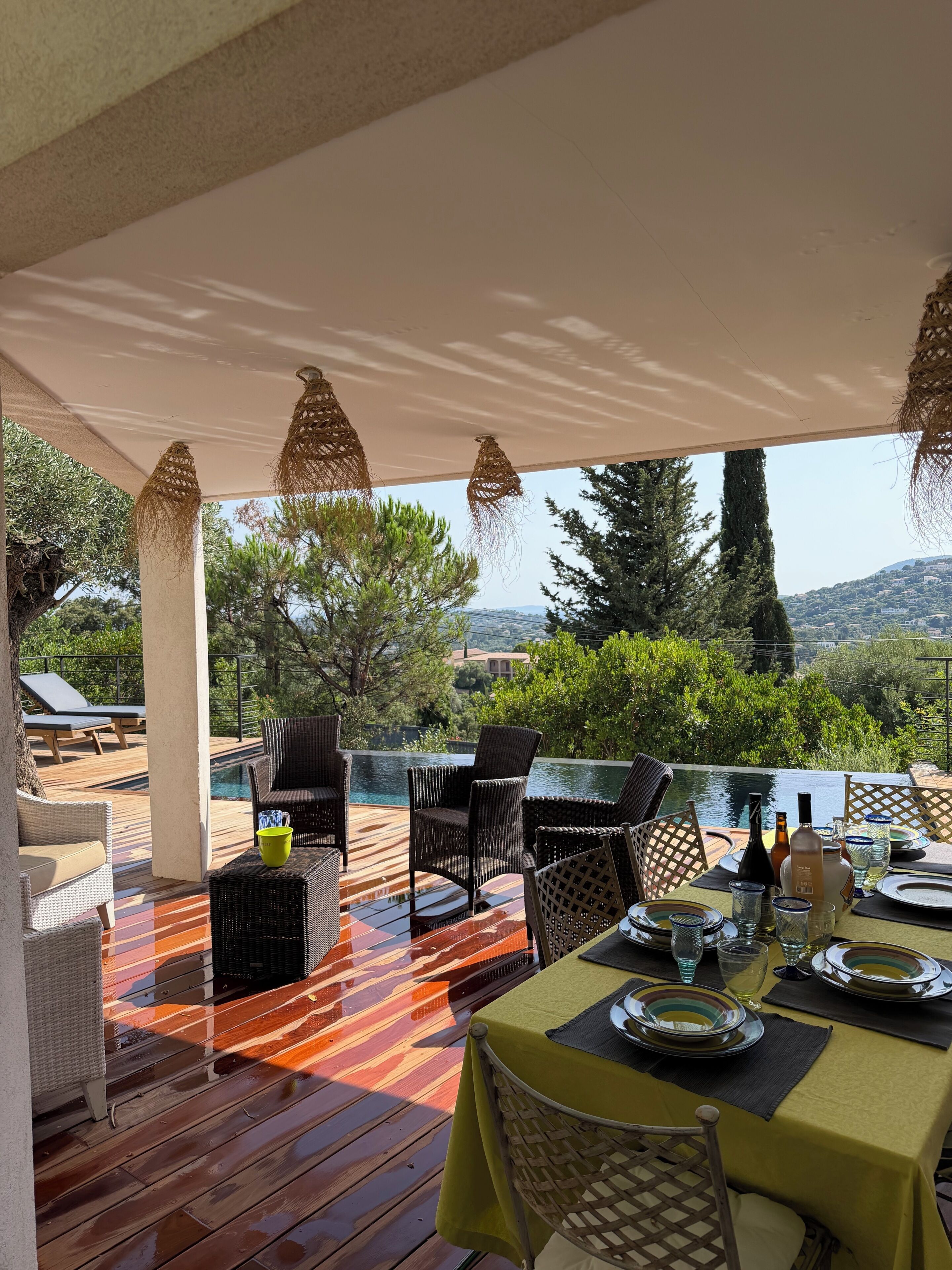 Un área de comedor al aire libre con mobiliario de mimbre, una piscina y vistas del paisaje.
