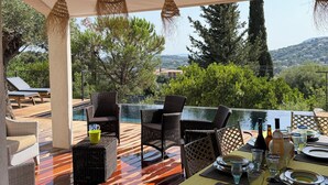 Ein Essbereich im Freien mit Korbmöbeln, einem Pool und Blick auf die Landschaft.