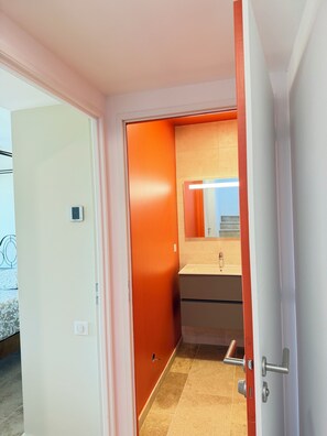 A hotel room with a bed, a bathroom with a mirror, and a door leading to another room. - NEW CHARMING VILLA WITH POOL, SEA VIEWS, AND HILLS, 1 KM FROM THE BEACH (Cavalaire-sur-Mer)
