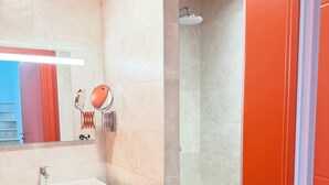 Ein modernes Badezimmer mit einem weißen Waschbecken, einem großen Spiegel, einer Dusche und einer roten Akzentwand.