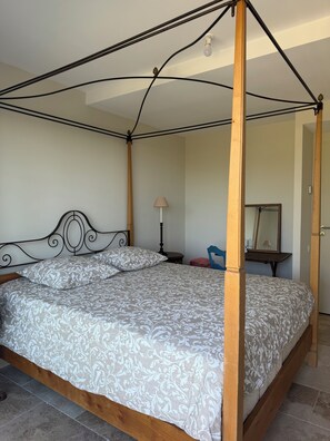 A four-poster bed with a patterned bedspread, a bedside table with a lamp, and a mirror on the wall. - NEW CHARMING VILLA WITH POOL, SEA VIEWS, AND HILLS, 1 KM FROM THE BEACH (Cavalaire-sur-Mer)
