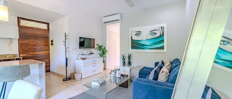 A modern living room with a sofa, coffee table, TV, and artwork.
