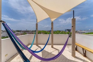 A rooftop terrace with a hammock, a bench, and a view of the cityscape. - Luxury apartment with pool & high speed WIFI (Playa del Carmen)