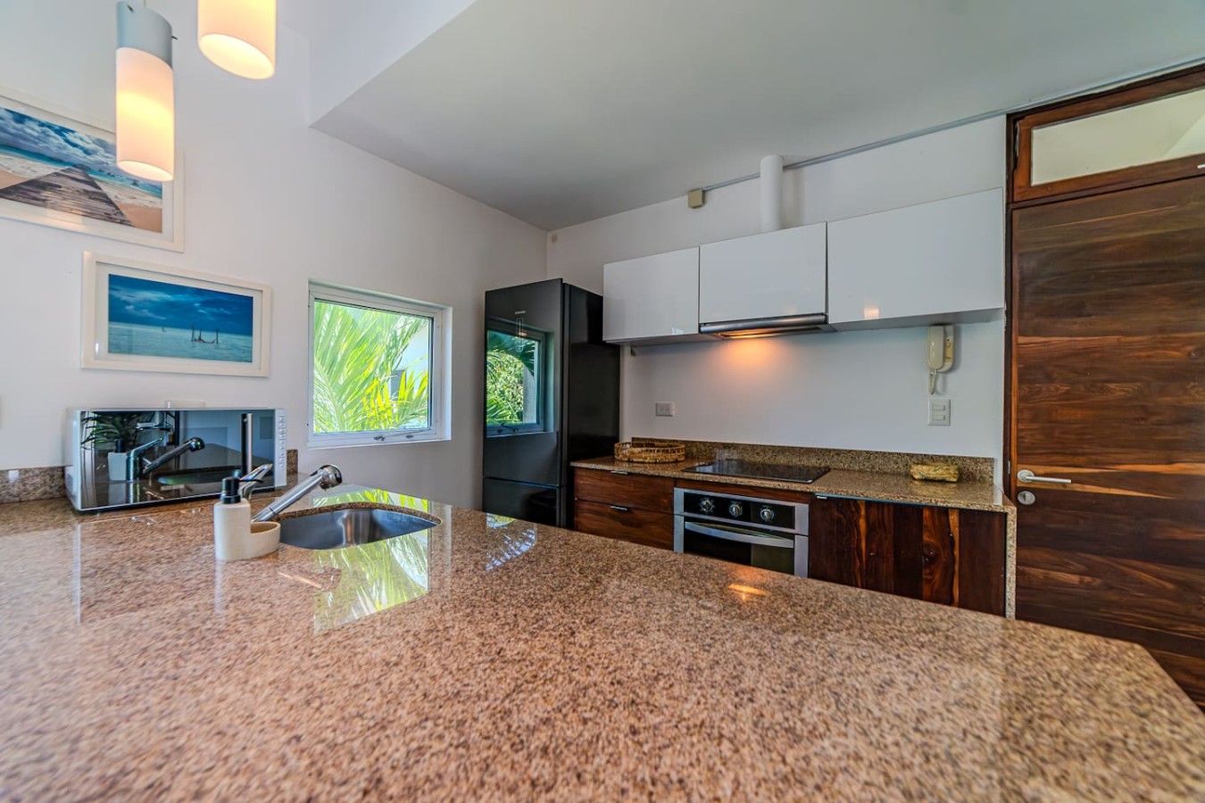 A modern kitchen with granite countertops, stainless steel appliances, and a wooden door.