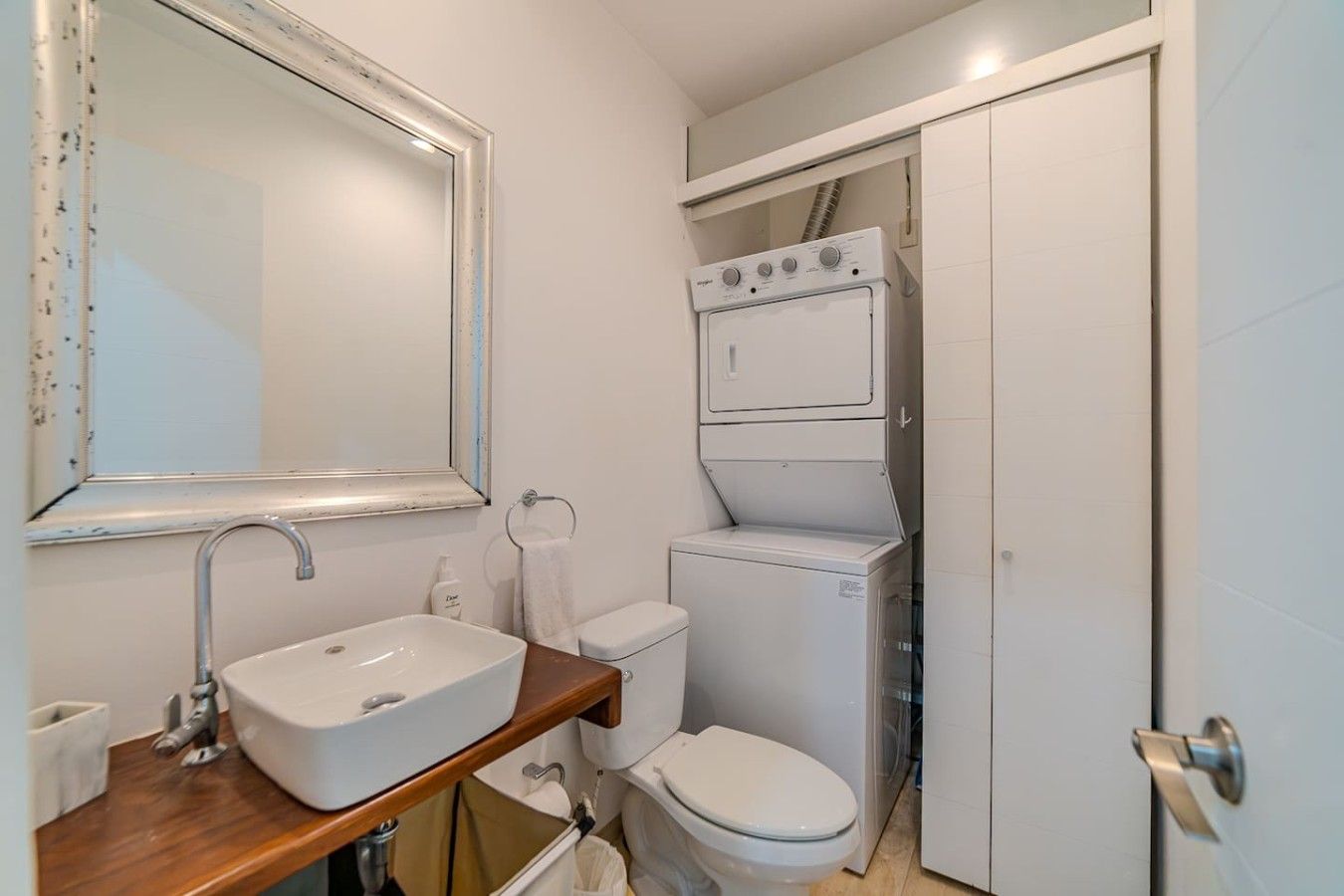 Un baño pequeño con lavamanos, espejo, inodoro y lavadora.
