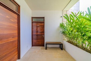 A hallway with a wooden door marked '201', a small bench, and a planter with green plants. - Luxury apartment with pool & high speed WIFI (Playa del Carmen)