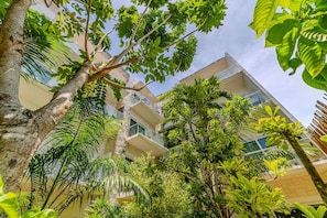 A multi-story building with balconies, surrounded by lush greenery and trees. - Luxury apartment with pool & high speed WIFI (Playa del Carmen)