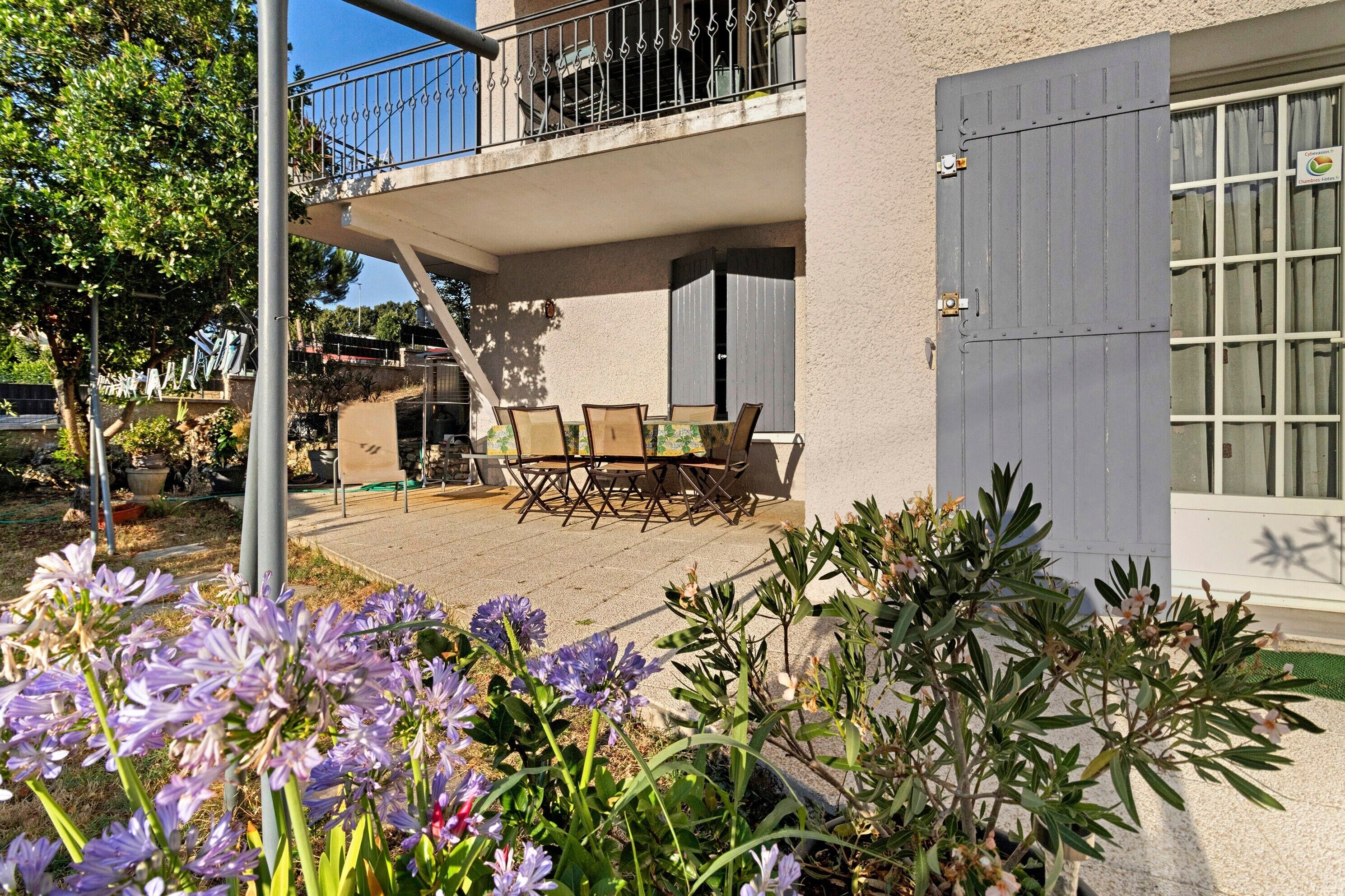 Un immeuble résidentiel doté d’un balcon, d’un espace extérieur aménagé pour s’asseoir et d’un jardin fleuri.