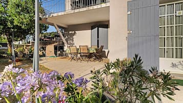A residential building with a balcony, outdoor seating area, and a garden with flowers.