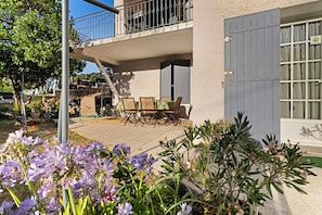 A residential building with a balcony, outdoor seating area, and a garden with flowers.