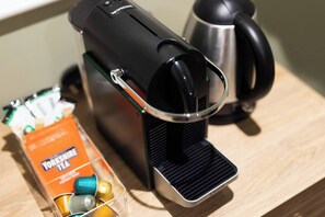 Una cafetera con espumador de leche, un hervidor y una caja de té Yorkshire sobre una superficie de madera.