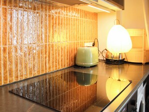 Eine Küche mit einem Toaster, einer Lampe und einer gefliesten Rückwand.