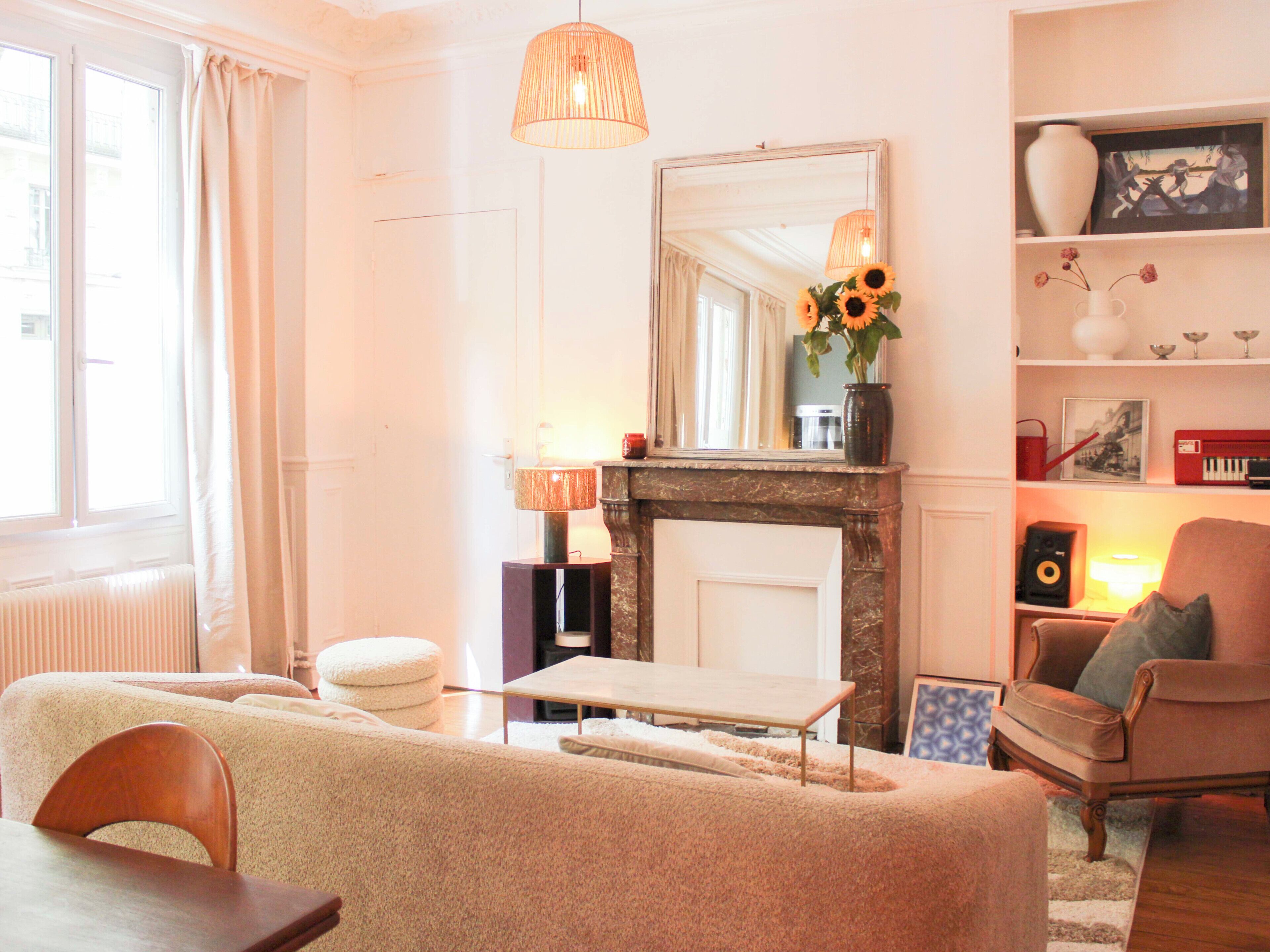 A living room with a fireplace, a sofa, a chair, a table, and a bookshelf.
