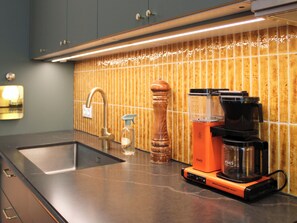 Uma cozinha com design moderno, com pia, cafeteira e espaço para temperos.