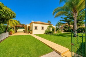 Ein Haus mit gepflegtem Rasen, einem gepflasterten Weg zum Eingang und einem eingezäunten Bereich.