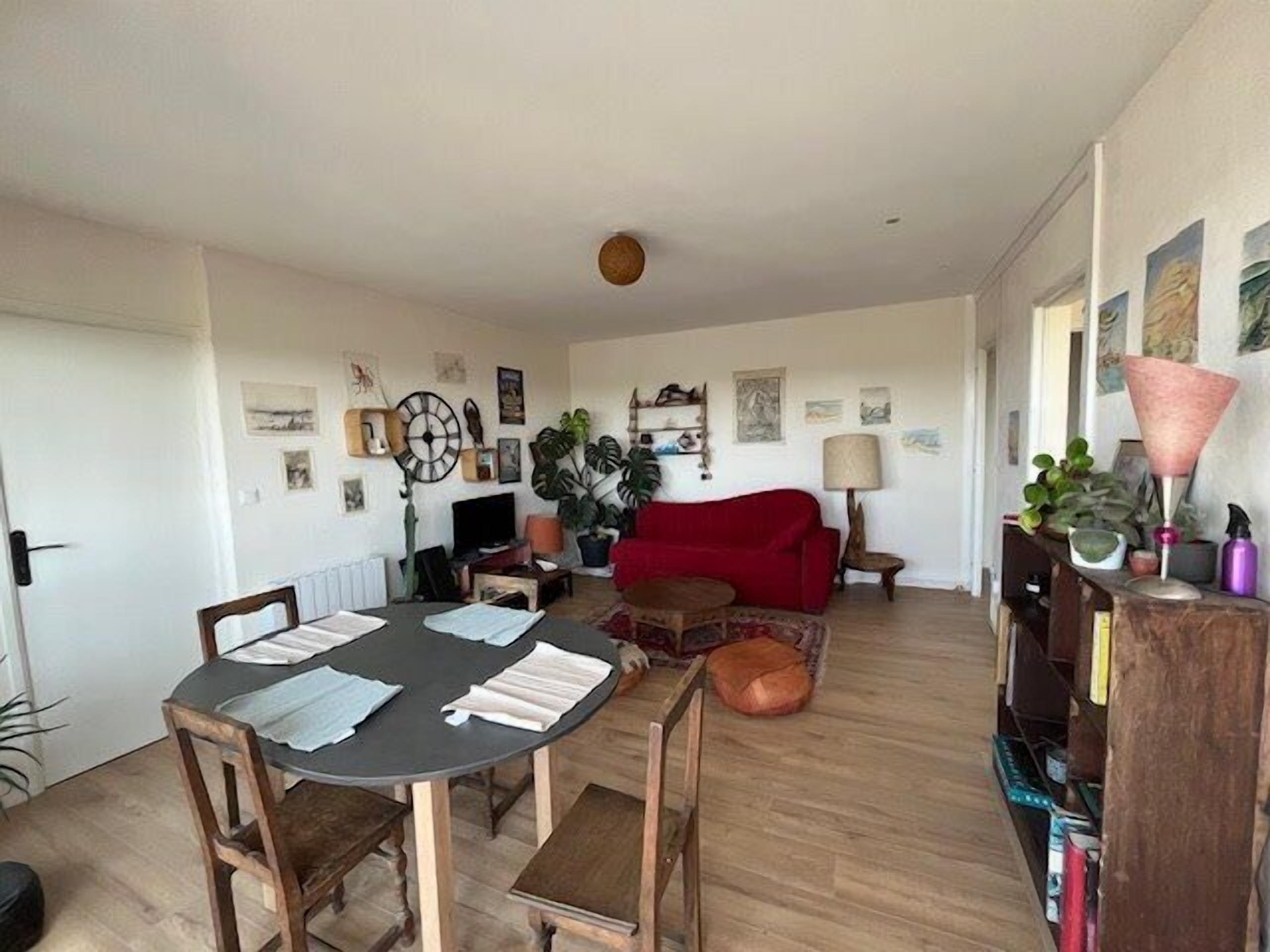 A dining area with a round table, chairs, and a red sofa.