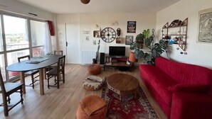 Uma sala de estar com um sofá vermelho, uma mesa de jantar de madeira e uma televisão.