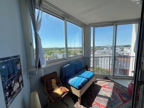 A balcony with a bed, a chair, and a view of the city. - Bright apartment with balcony in Vannes (Vannes)