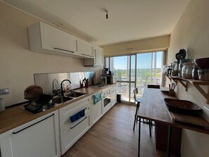 A modern kitchen with white cabinets, a wooden countertop, and a large window offering a city view. - Bright apartment with balcony in Vannes (Vannes)