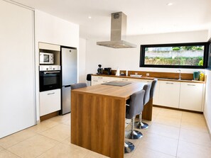 A modern kitchen with a central island, built-in appliances, and a window with a view. - Spacious house with sea and mountain views (BASTELICACCIA)
