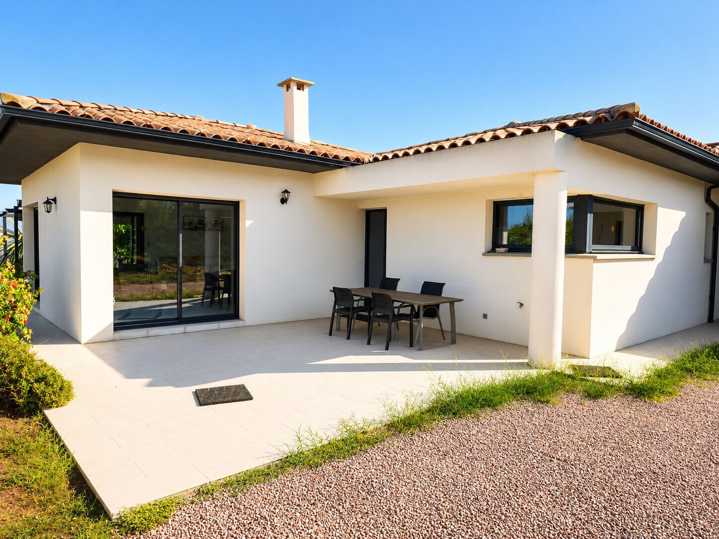 Uma casa moderna com um pátio, espaço para refeições e uma chaminé.