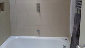 Ein Badezimmer mit Badewanne, Dusche und Handtuchhalter.