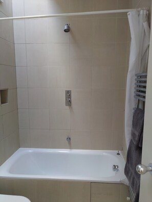 Ein Badezimmer mit Badewanne, Dusche und Handtuchhalter.