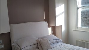 Ein Schlafzimmer mit einem Bett, Nachttischen, einem Fenster und eingebauten Schränken.