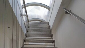 Eine Metalltreppe mit Oberlicht darüber, die zu einer Ebene darunter führt.