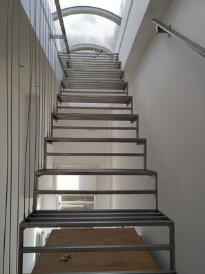 Eine Metalltreppe mit Oberlicht darüber, die zu einer Ebene darunter führt.
