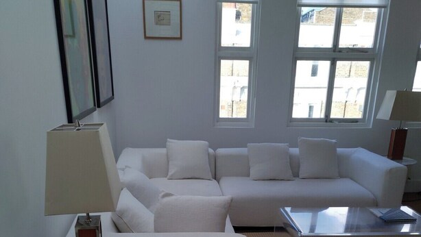 Ein modernes Wohnzimmer mit einem weißen Sofa, einem runden Couchtisch und einem Beistelltisch mit Lampe.