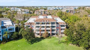 A multi-story residential building with a central courtyard, surrounded by greenery and other residential structures. - New! Epic Reunion Family Retreat (Kissimmee)