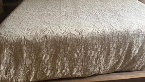 A bed with a patterned bedspread, a headboard, and decorative pillows.