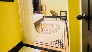 Une chambre d’hôtel avec un lit, une petite table, une chaise et un tapis décoratif.