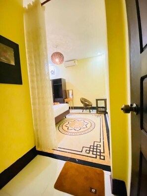 A hotel room with a bed, a small table, a chair, and a decorative rug.