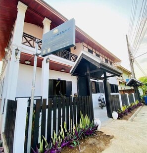A hotel entrance with a sign, a covered walkway, and a vehicle parked outside.