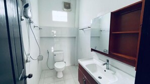 A bathroom with a toilet, a sink, a mirror, and a shower.