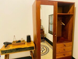 A wooden cabinet with a mirror, a small table with a tray of items, and a patterned floor.