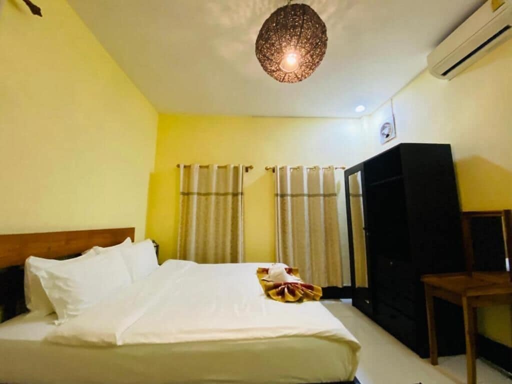 Quarto de hotel com cama, cortinas, guarda-roupa e luminária no teto.