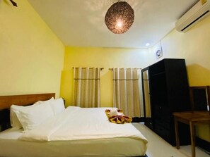 A hotel room with a bed, curtains, a wardrobe, and a ceiling light fixture.