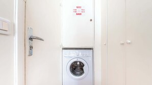Ein Waschraum mit Waschmaschine, einer Tür mit Sicherheitsschild und einem Lichtschalter.